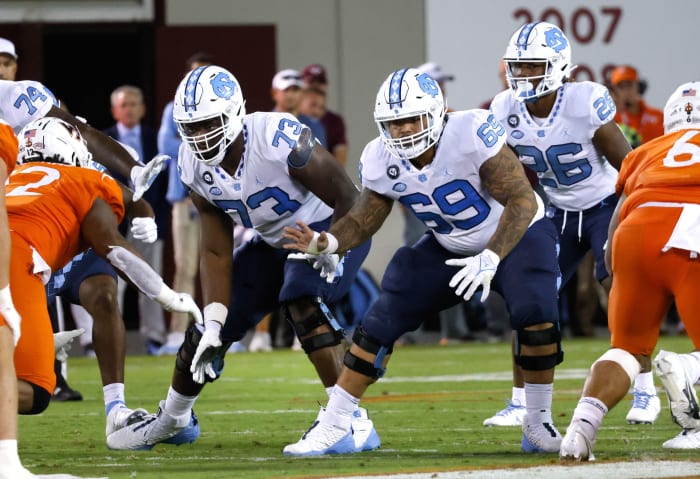 Sep 3, 2021; Blacksburg, Virginia, USA; North Carolina Tar Heels offensive linemen Marcus McKethan (73) and Quiron Johnson (69) and running back D.J. Jones (26) react to the snap during the second half against the Virginia Tech Hokies at Lane Stadium.